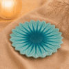 Blauw keramisch lotus bord van 27 cm op beige stof in een warme sfeersetting met zachte verlichting.