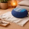 Rond Thais meditatiekussen in blauw met traditioneel patroon in een rustige, warme woonsetting.