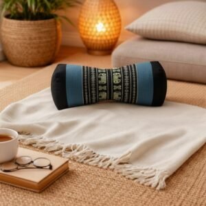 Thais bone nekrolkussen in zwart en grijsblauw met olifantpatroon, geplaatst op een beige plaid in rustgevend interieur.