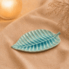 Blauwe keramische bladschaal van 21 cm op beige stof in een warme sfeersetting.