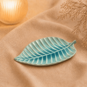 Blauwe keramische bladschaal van 21 cm op beige stof in een warme sfeersetting.