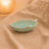 Blauw keramisch bladschaaltje van 17 cm met bladreliëf in warme sfeersetting op beige stof.