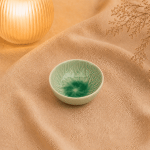 Groen keramisch bloemschaaltje van 8 cm in warme sfeersetting op beige stof.