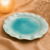 Blauwe bloemvormige keramische lotus schaal van 30 cm op beige stof in een warme sfeersetting.