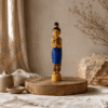 Blauw met goudkleurig Sawadee Lady beeld van 36 cm op ronde houten verhoger in naturel interieur met linnen stoffen en droogbloemen.