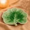 Groene serveerbord Lotus van 23,5 cm in bladvorm met sierlijk nervenpatroon, sfeervol gepresenteerd.