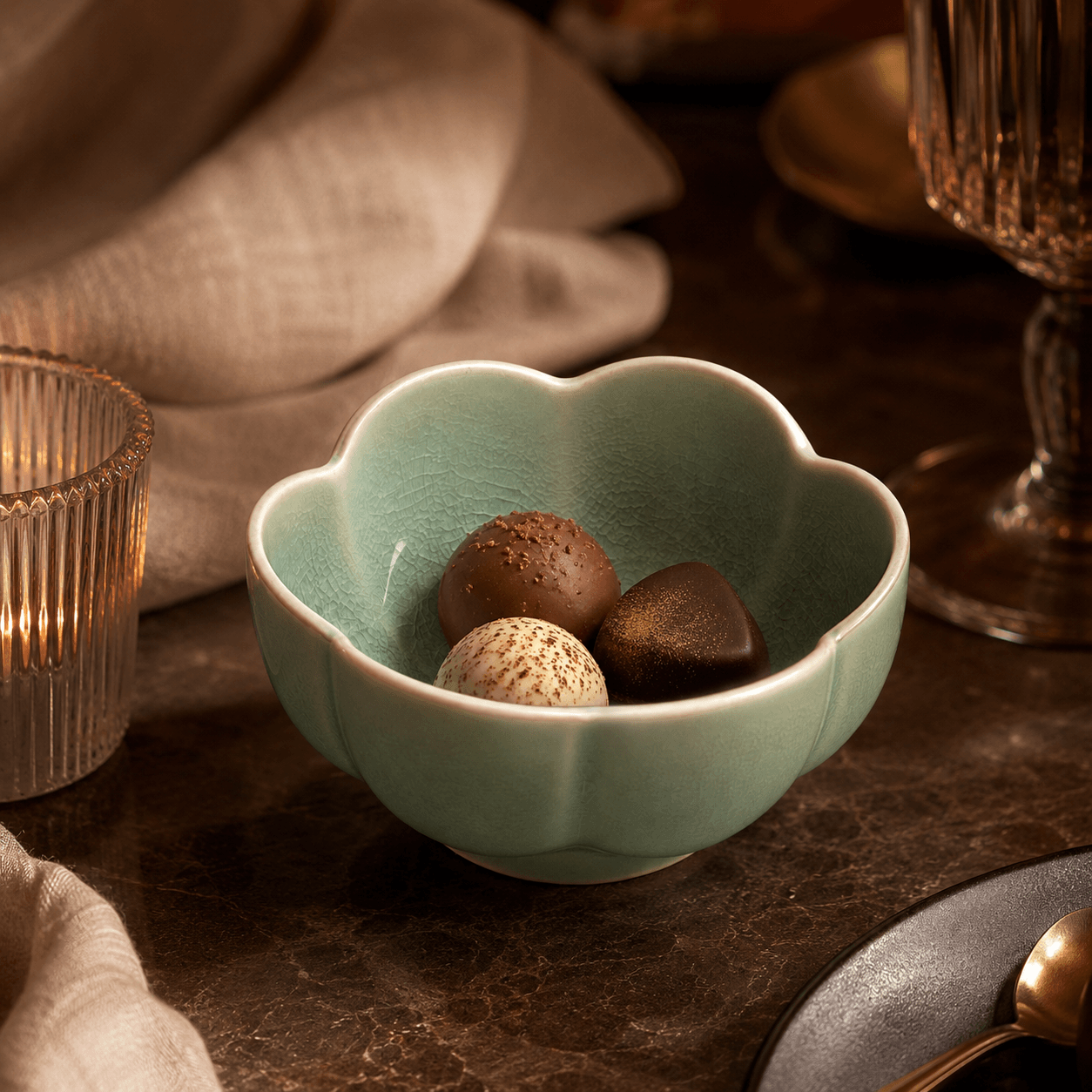 Groen bloemschaaltje van 9 cm met bonbons op een warme sfeervolle tafel.