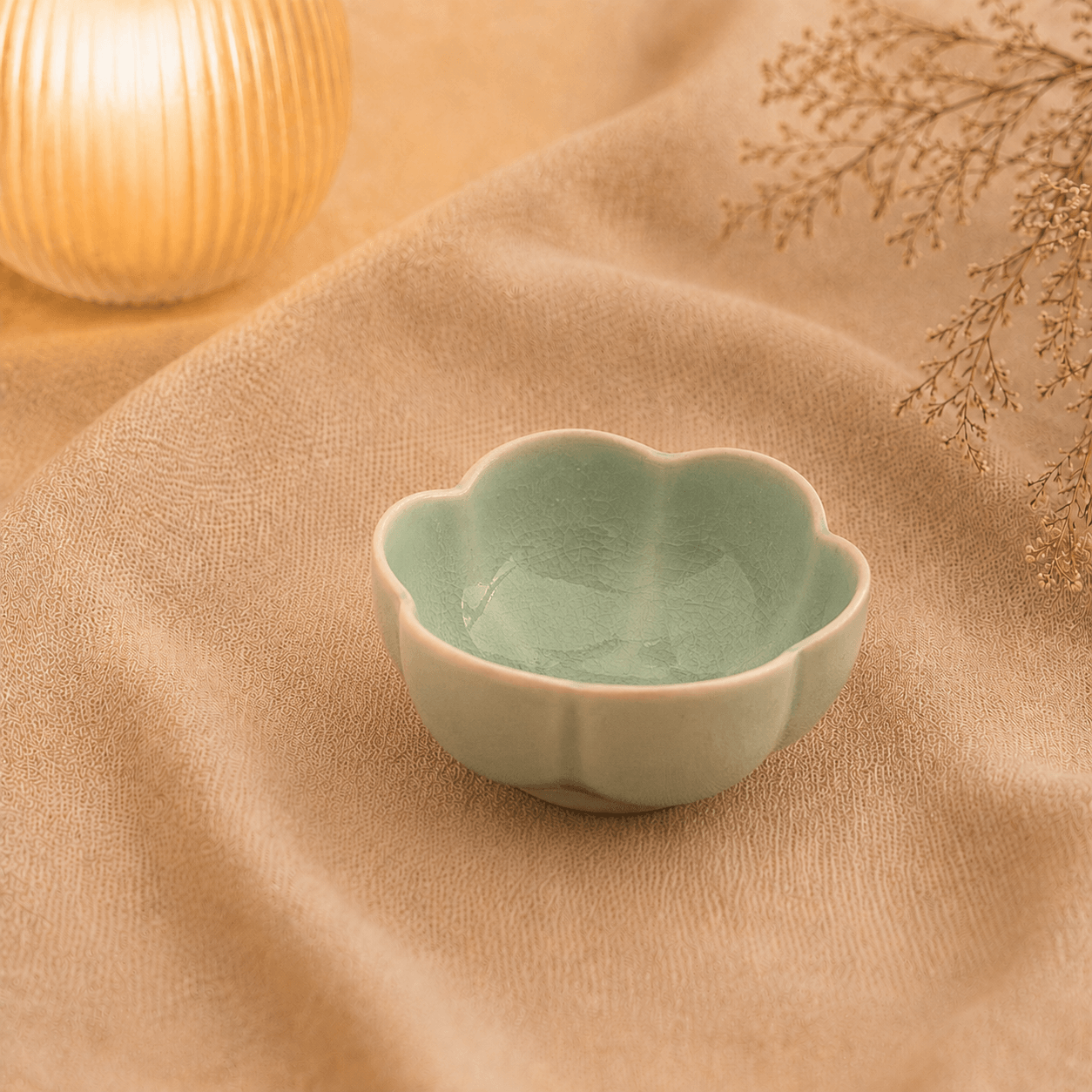 Groen bloemschaaltje van 9 cm in bloemvorm op beige stof met warme sfeerverlichting.