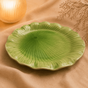 Groene bloemvormige keramische lotus schaal van 30 cm op beige stof in een warme sfeersetting.