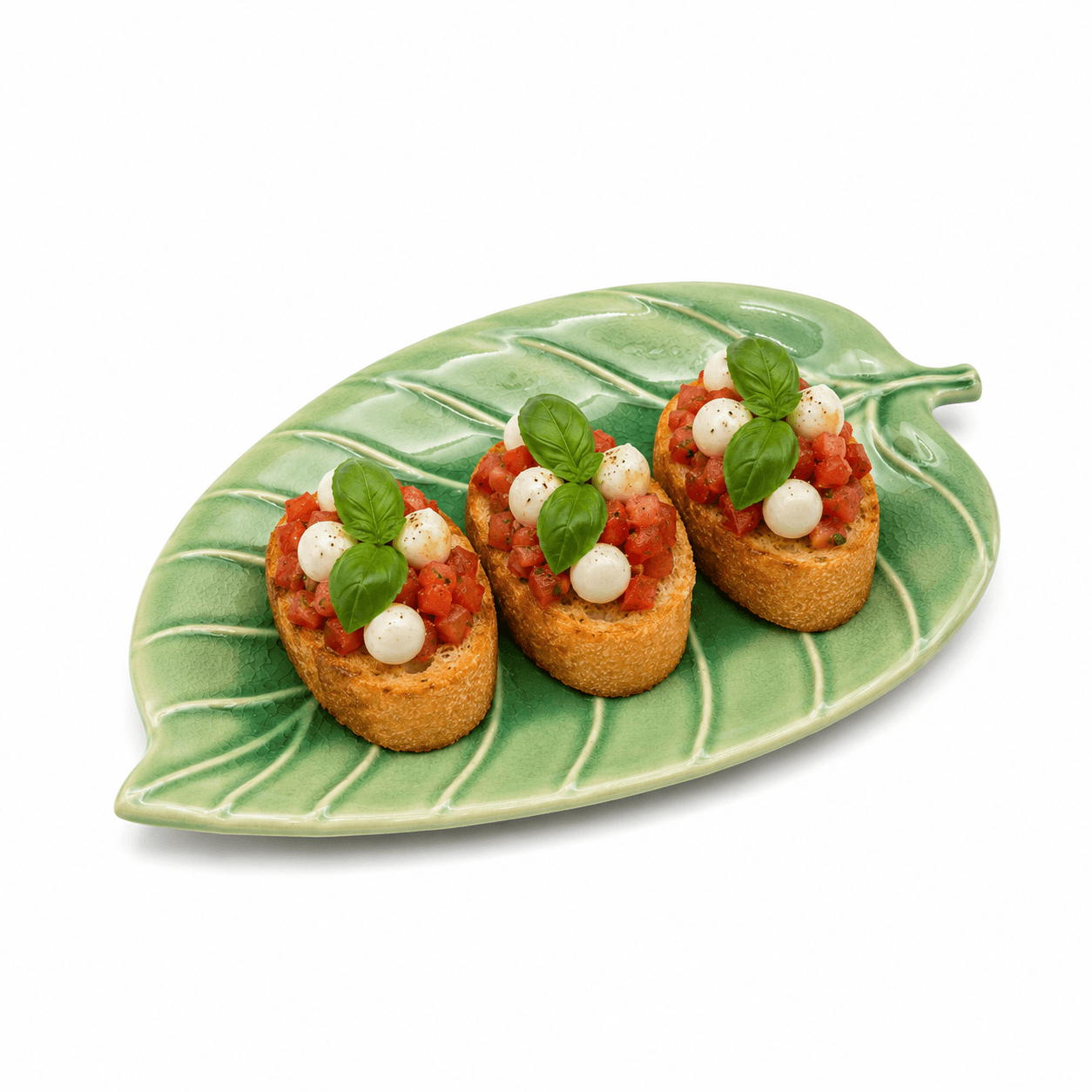 Groene keramische schaal in bladvorm van 24 cm met drie bruschetta’s met tomaat, mozzarella en basilicum.