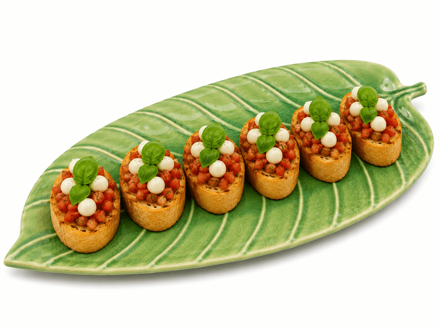 Groene keramische schaal in bladvorm van 28 cm met vijf bruschetta’s met tomaat, mozzarella en basilicum.