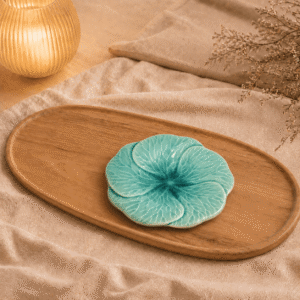 Blauw keramisch lotus bloembord van 18 cm op een houten dienblad met beige stof en warme verlichting.
