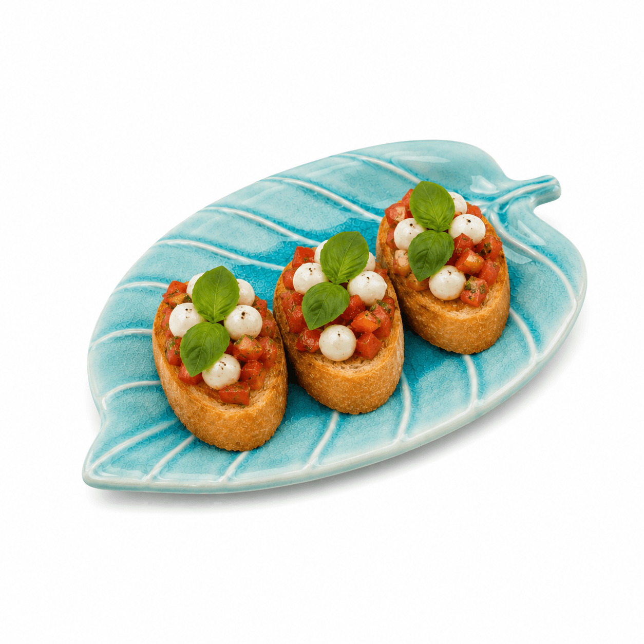 Blauwe keramische schaal in bladvorm van 21 cm met drie bruschetta’s met tomaat, mozzarella en basilicum