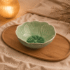 Groene bloemvormige serveerschaal van 22 cm op een houten plateau in een warme sfeersetting.