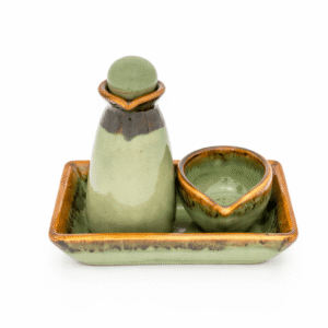 Groene keramische massage olie karaf met bijpassend schaaltje op een rechthoekig dienblad, vrijstaand op lichte achtergrond.