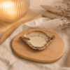 Crème bruin keramisch schaaltje in bladvorm op houten plateau in warme sfeersetting met lamp en beige stof.