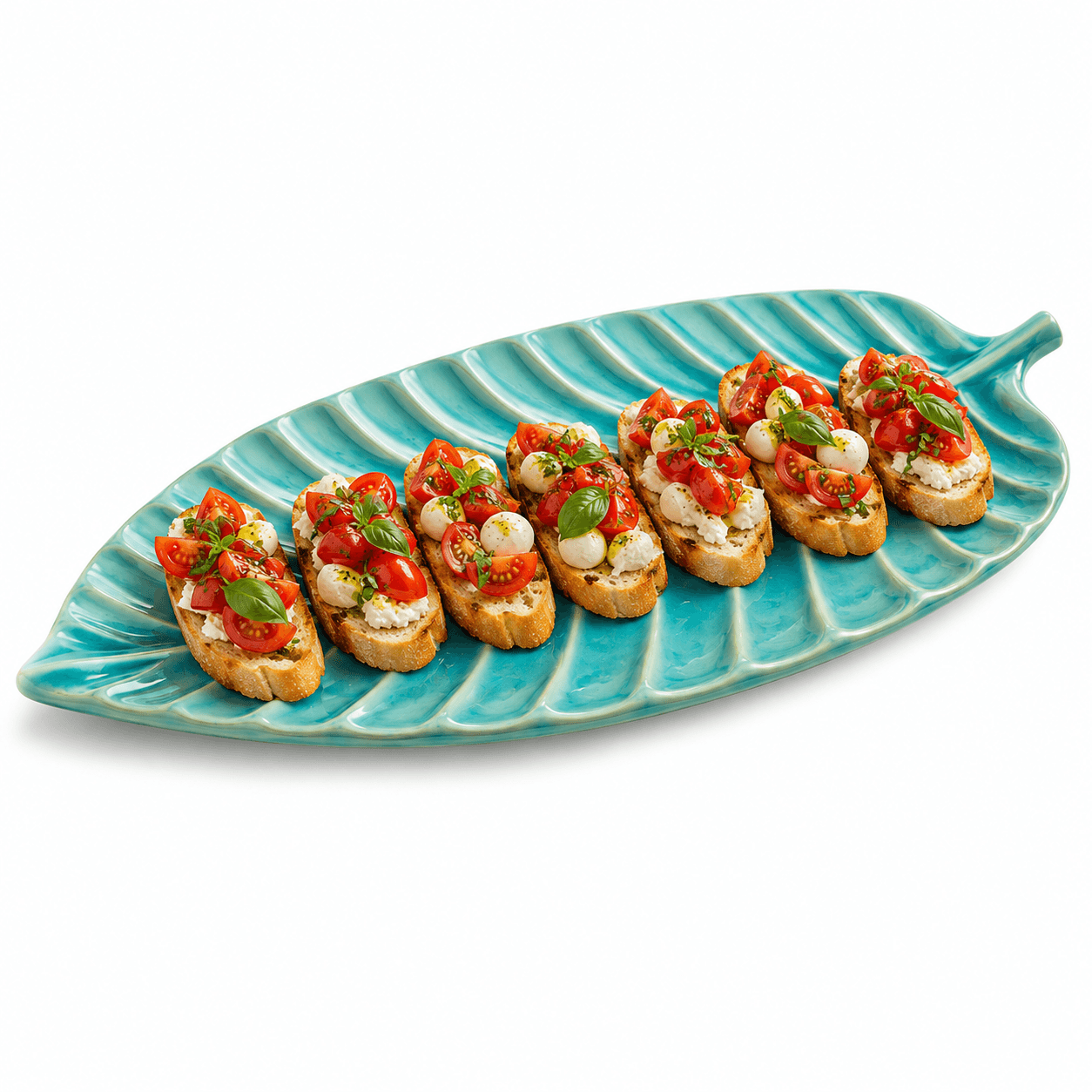 Blauwe keramische bladschaal met meerdere bruschetta’s met tomaat, mozzarella en basilicum op een witte achtergrond.