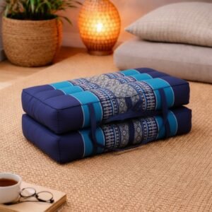 Opgevouwen Thais meditatiekussen in donkerblauw en turquoise met licht traditioneel patroon in een warme en rustgevende interieursetting.