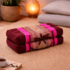 Opgevouwen Thais meditatiekussen in bordeaux en fuchsia roze met licht traditioneel patroon in een warme en rustgevende interieursetting.