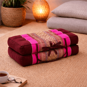 Opgevouwen Thais meditatiekussen in bordeaux en fuchsia roze met licht traditioneel patroon in een warme en rustgevende interieursetting.