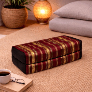 Rechthoekig Thais meditatiekussen met rood-gouden silklook strepen in een warme en sfeervolle interieursetting.