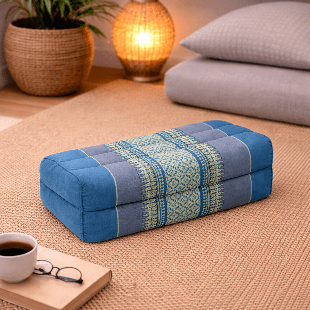 Rechthoekig Thais meditatiekussen in lichtblauw en grijs met traditioneel patroon in een warme interieursetting.