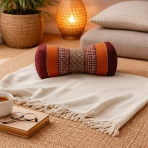 Oranje Thais bone meditatiekussen met bordeaux accenten en traditioneel patroon in sfeervol interieur.