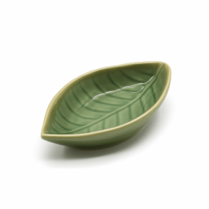 Keramisch schaaltje in de vorm van een blad, glanzend lichtgroen van kleur, op witte achtergrond.