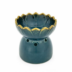 Blauwgroene aromabrander met brandend theelichtje en opstijgende geurrook op houten tafel in een rustgevende spa-omgeving.