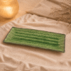 Groene rechthoekige keramische serveerschaal van 29 cm op beige stof in een warme sfeersetting.