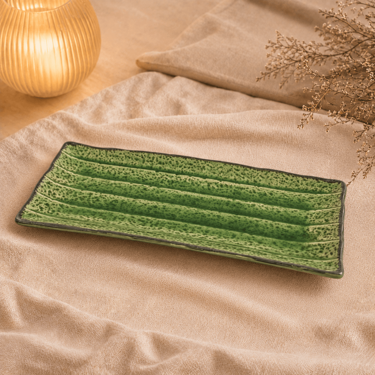 Groene rechthoekige keramische serveerschaal van 29 cm op beige stof in een warme sfeersetting.