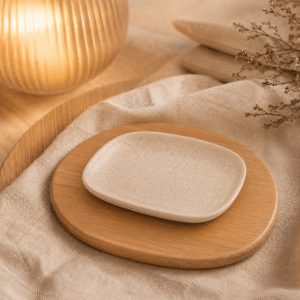 Schaal Dao ovaal klein wit gespikkeld op een houten onderzetter met warme verlichting, beige textiel en natuurlijke decoratie.