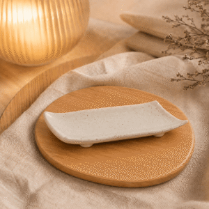 Schaal Dao wit gespikkeld op een houten onderzetter met warme verlichting, beige textiel en natuurlijke decoratie.