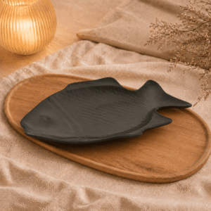 Zwart keramisch visbord van 38 cm op een houten dienblad met beige stof en warme sfeerverlichting.