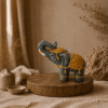 Stenen olifant in grijs-goud met opgeheven slurf in een warme natuurlijke interieursetting.