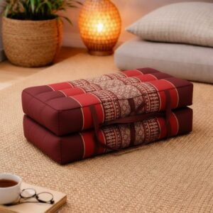 Opgevouwen Thais meditatiekussen in bordeaux rood met traditioneel patroon in een warme en rustgevende interieursetting.
