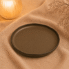 Diep bord mat bruin 24 cm op een warme stoffen ondergrond met zachte verlichting en natuurlijke styling.