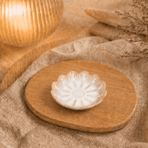 Wit keramisch lotusschaaltje met beige accenten op een houten plateau in warme sfeersetting.