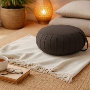 Rond Thais zafu kussen in effen donkerbruin in een sfeervolle woonsetting met plaid en warme verlichting.