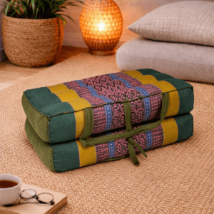 Opgevouwen Thais meditatiekussen in donkergroen, geel en roze in een warme en rustgevende interieursetting.