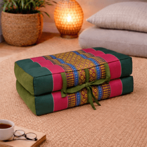 Opgevouwen Thais meditatiekussen in donkergroen en roze met traditioneel patroon in een warme en rustgevende interieursetting.