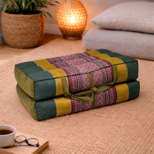 Opgevouwen Thais meditatiekussen in donkergroen, mosterdgeel en bordeaux in een warme en rustgevende interieursetting.