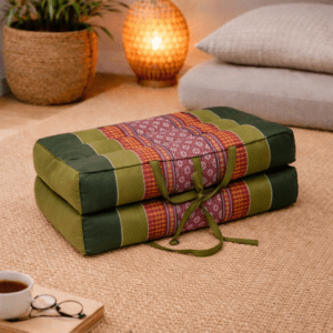 Opgevouwen Thais meditatiekussen in olijfgroen en roestrood met traditioneel patroon in een warme en rustgevende interieursetting.