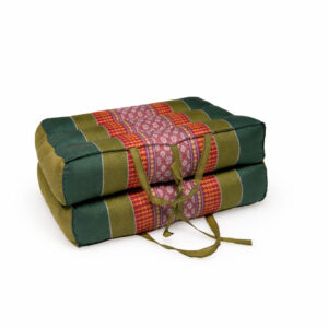 Opgevouwen meditatiekussen in olijfgroen met rood patroon, compact vastgebonden en geschikt om op te bergen of mee te nemen.