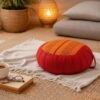 Rond Thais meditatiekussen in rood en oranje met traditioneel geweven patroon in een sfeervol interieur.