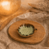 Groen-bruin keramisch bladschaaltje op een houten dienblad in een warme sfeersetting met zachte verlichting.