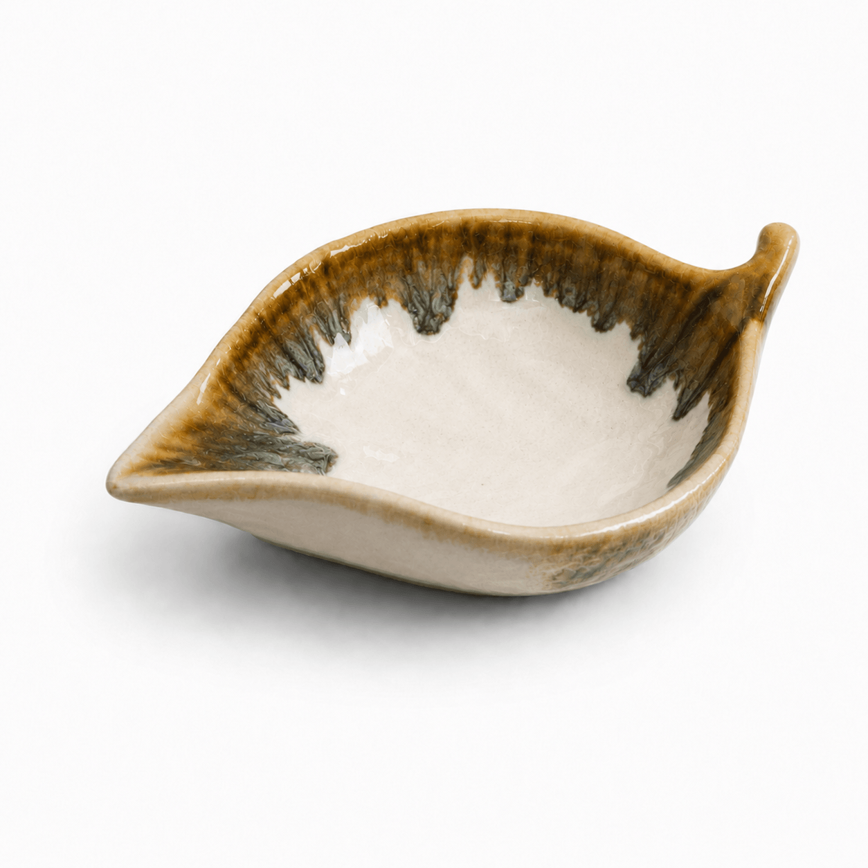 Witbruin keramisch schaaltje in bladvorm met glanzend glazuur en donkere rand op witte achtergrond.
