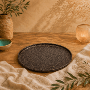 Zwart-bruin gespikkeld plat bord van 25,5 cm op een houten tafel met warme natuurlijke styling.