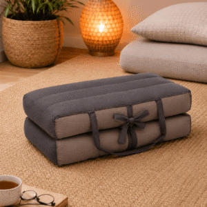 Draagbaar meditatiekussen in grijs en beige op een naturel vloerkleed in een warme meditatiehoek met sfeerlamp.