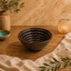 Zwart-bruin gespikkelde keramische kom van 13 cm op een houten tafel met warme natuurlijke styling.